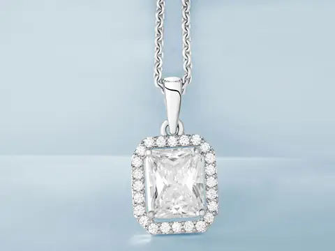 A radiant-cut diamond pendant with a halo of small diamonds on a white gold chain