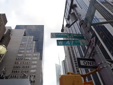 The W 47 St and Diamond Jewelry Way signs at Sixth Avenue, looking up at the office towers of Midtown
