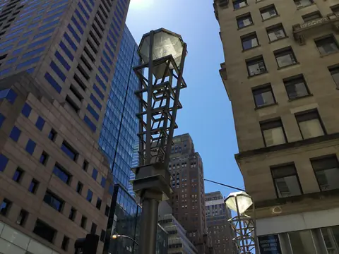 Diamond District lamp posts, each topped with a glass diamond, under a blue sky between Midtown office towers
