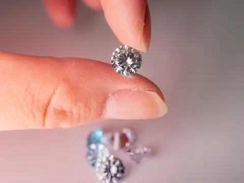 A loose round brilliant diamond held between finger and thumb