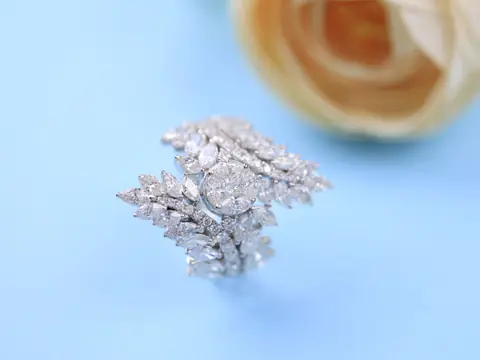 A white gold ring of marquise and round diamonds on a pale blue ground